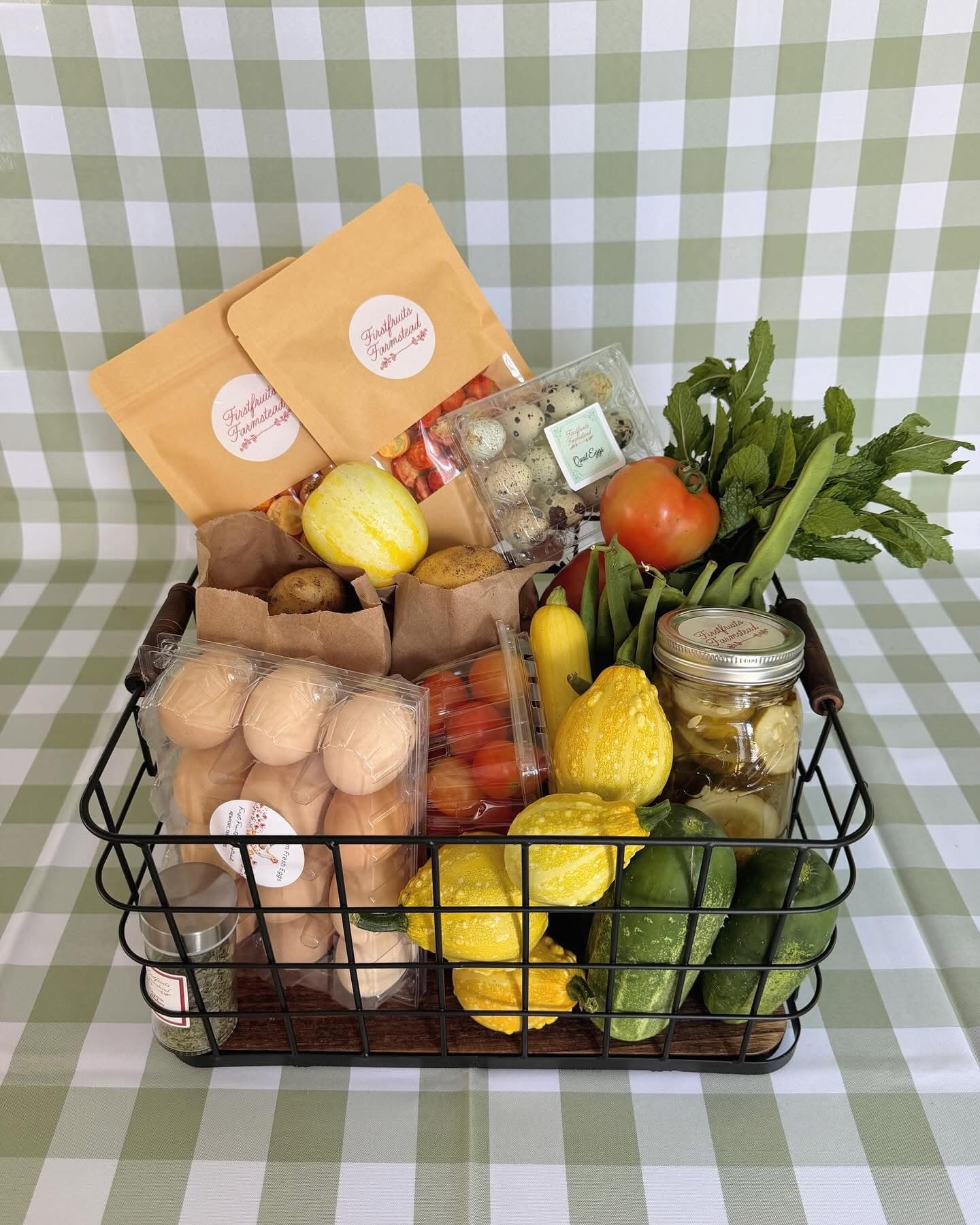 Basket of farm-fresh eggs, quail eggs, squash, cucumbers, tomatoes, herbs, and pickles